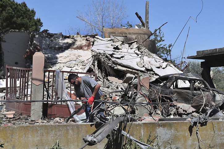 Un électricien libanais répare des câbles électriques devant une maison détruite par une frappe aérienne israélienne, à Alma al-Shaab, un village libanais frontalier avec Israël, dans le sud du Liban, Tsahal répondant à une attaque du Hezbollah. © KEYSTONE/AP/Mohammad Zaatari