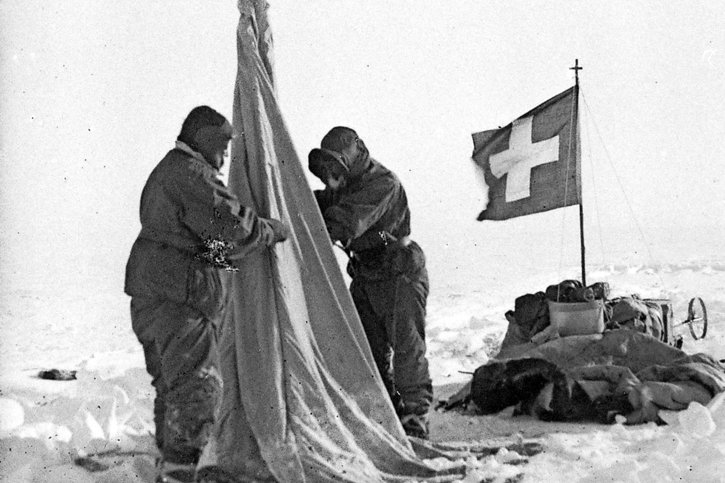 Le Bâlois Xavier Mertz est le premier explorateur à hisser le drapeau suisse en Antarctique (ici lors d’une excursion au sud du cap Denison, en septembre 1912). En bas, Mertz, Ninnis et Murphy (de g. à dr.) en route pour le dépôt de provisions d’Aladdin’s Cave, situé à 9 km du camp de base.  © State Library of New South Wales