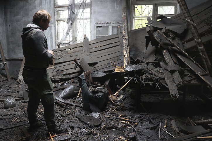 Une femme contemple les restes d'une maison détruite à Donetsk, dans l'est de l'Ukraine. © KEYSTONE/AP/Alexei Alexandrov
