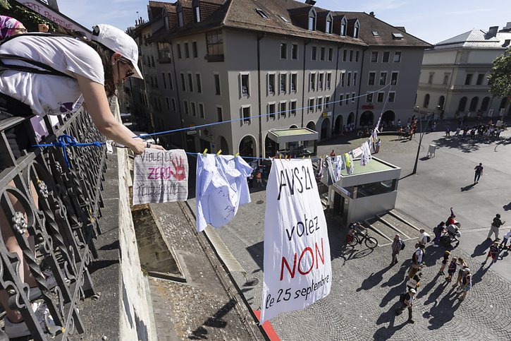 Des militantes suspendent sur un fil des vêtements sur lesquels sont inscrites des revendications, lors de la manifestation à Lausanne. © KEYSTONE/CYRIL ZINGARO