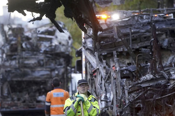 Un employé déblaie les débris près de véhicules de transport endommagés dans les émeutes à Dublin. © KEYSTONE/AP/Brian Lawless