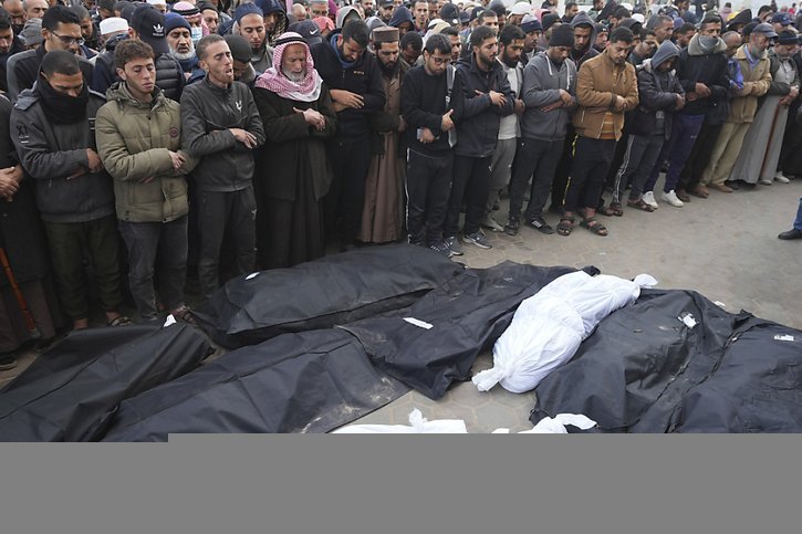 Des personnes prient sur les corps de leurs proches tués dans des bombardements israéliens sur Deir al Balah. © KEYSTONE/AP/Adel Hana