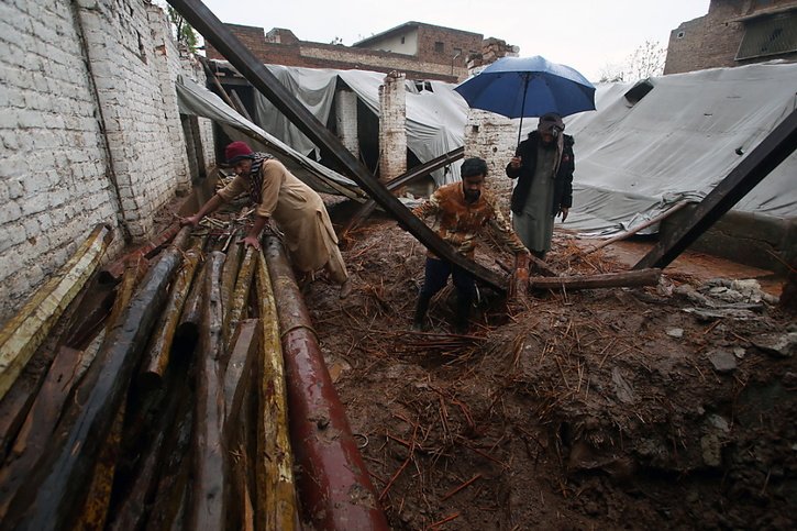 Des personnes récupèrent des avoirs de leur maison effondrée à Peshawar, dans la province de  Khyber Pakhtunkhwa. © KEYSTONE/EPA/ARSHAD ARBAB