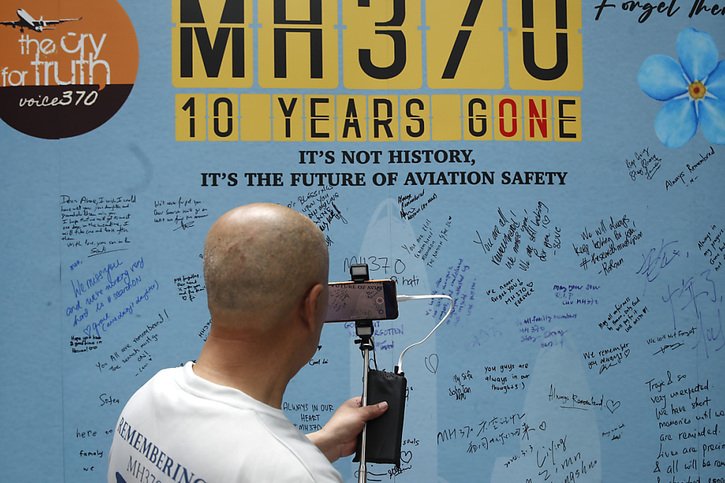 Un membre de la famille d'un passager chinois du vol 370 de Malaysia Airlines filme le panneau d'affichage lors de la dixième cérémonie annuelle de commémoration dans un centre commercial à Subang Jaya, dans la banlieue de Kuala Lumpur. © KEYSTONE/AP/FL Wong